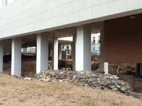 Los restos vistos desde el exterior: el muro corre bajo el edificio de las Consejerías, que hace de cubierta