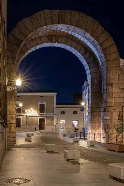 El arco iluminado de noche, en la plaza